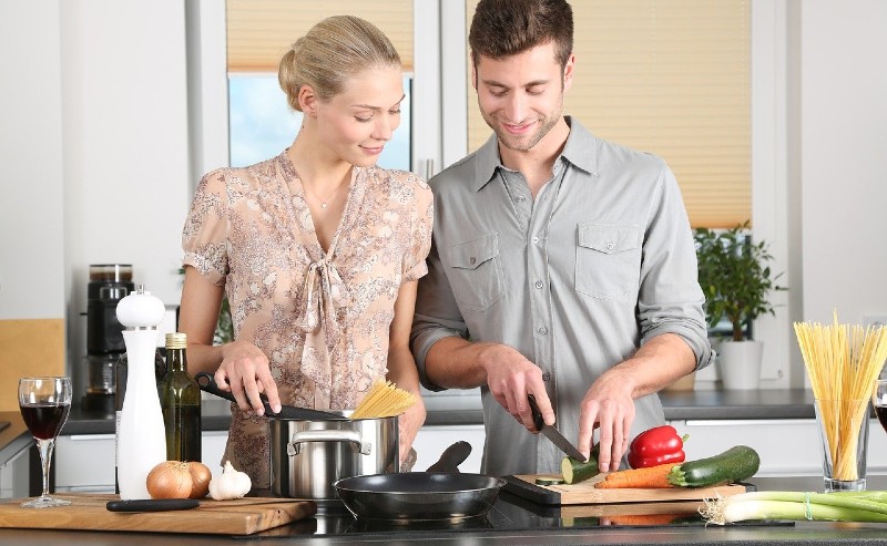 jeune couple qui prépare et découpe des légumes sur une planche à découper