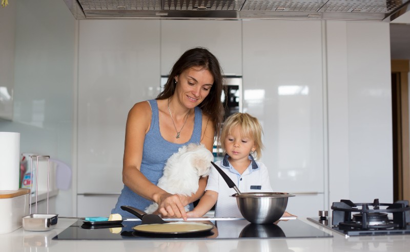 une femme qui fait des crêpes avec son enfant devant une poêle à crêpes