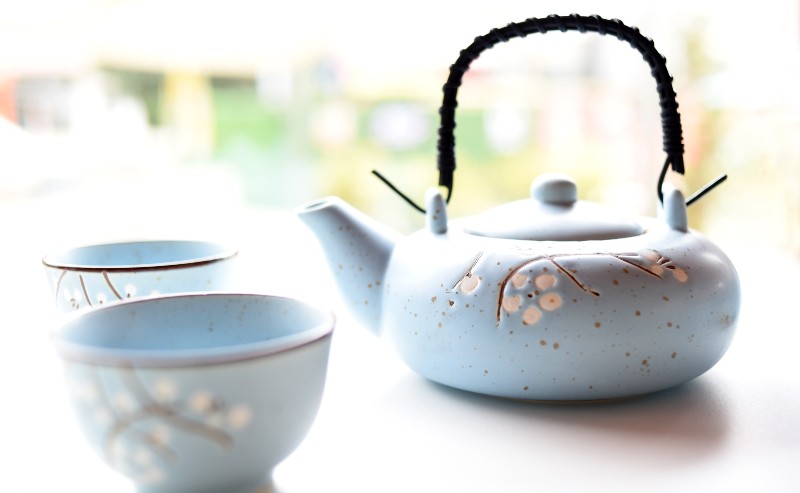 un joli service à thé bleu ciel composé de deux tasses et une théière posé sur table bien lumineuse