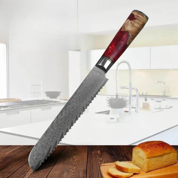 Couteau pain lame acier damas manche résine rouge posé en diagonale de la photo sur une table en bois et avec comme fond une cuisine.