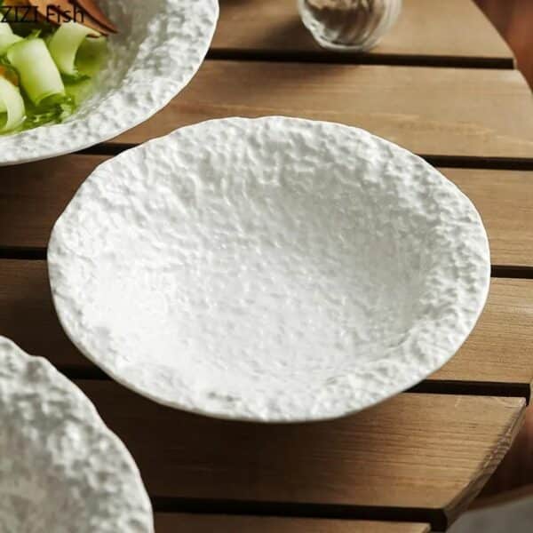 Assiette pates raffinee artistique présentée sur une table en bois. L'assiette est de couleur blanche
